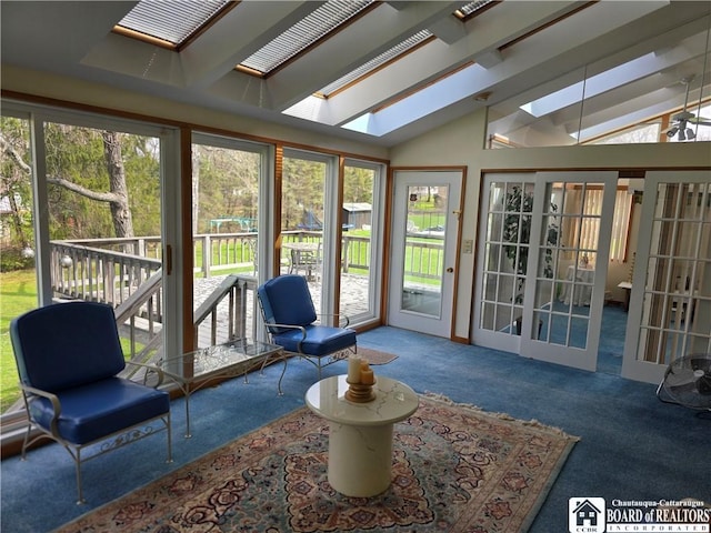 sunroom featuring a wealth of natural light, lofted ceiling with skylight, and carpet