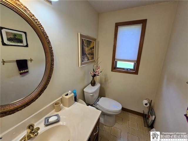 half bathroom with baseboards, toilet, and vanity