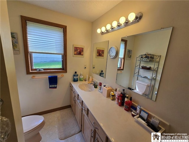 bathroom featuring vanity, toilet, a textured ceiling, baseboards, and tile patterned flooring