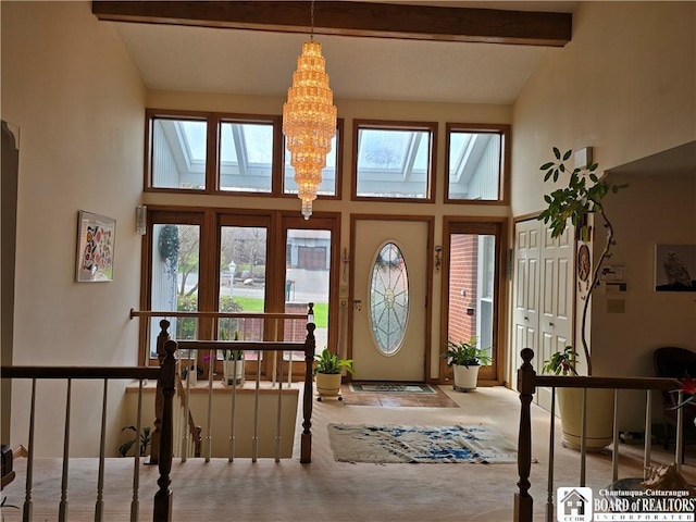 entryway with beamed ceiling, a towering ceiling, a chandelier, and carpet floors