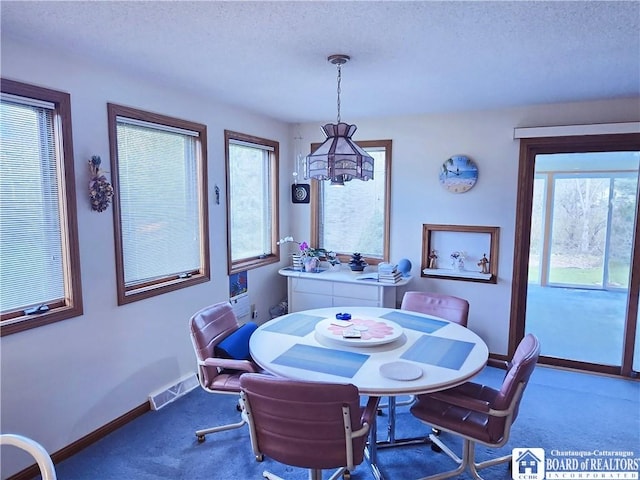 carpeted dining space featuring baseboards, visible vents, a chandelier, and a textured ceiling