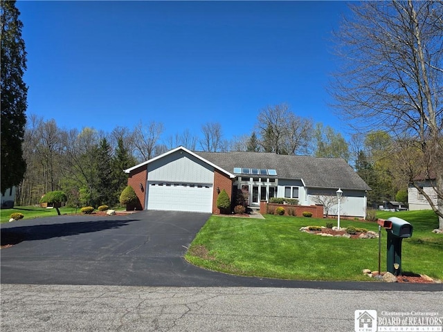 single story home featuring driveway, a front yard, brick siding, and a garage