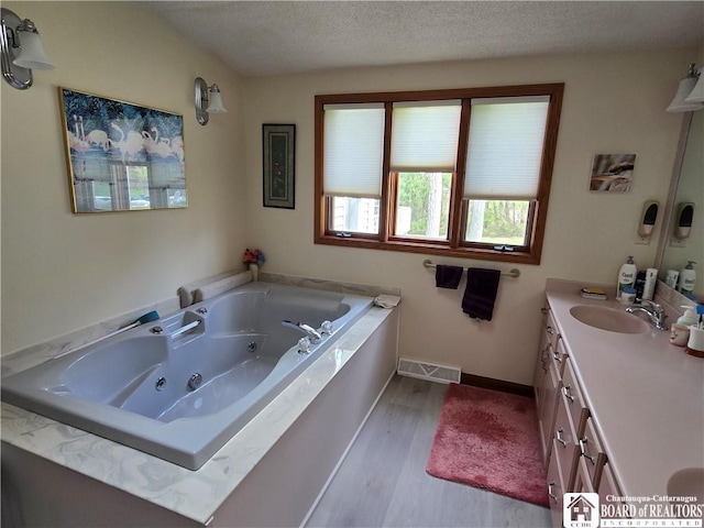bathroom featuring visible vents, baseboards, a tub with jets, wood finished floors, and vanity
