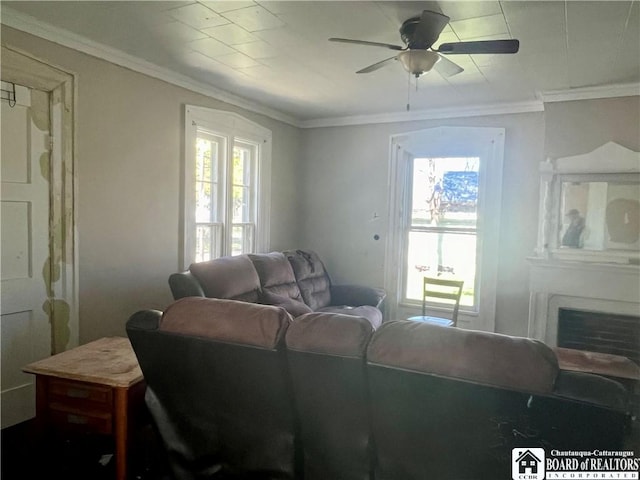 living area featuring crown molding, a ceiling fan, and a wealth of natural light