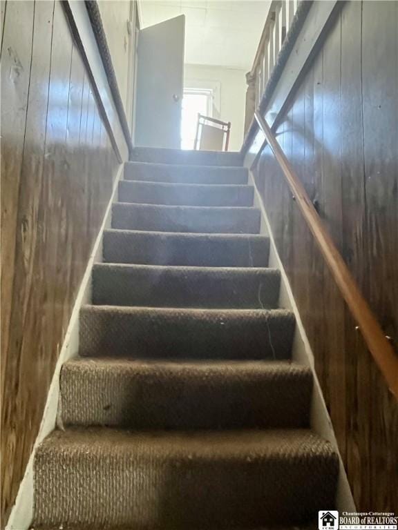 staircase featuring wood walls