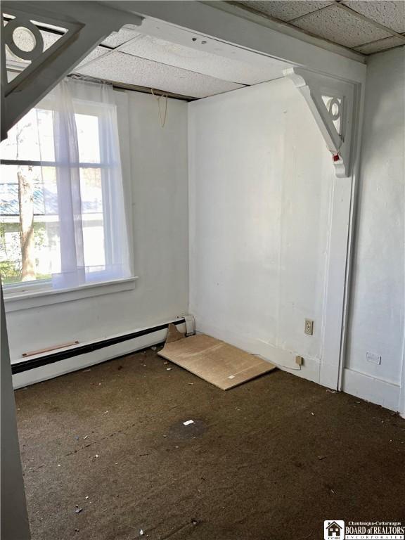 unfurnished room featuring a paneled ceiling and baseboard heating