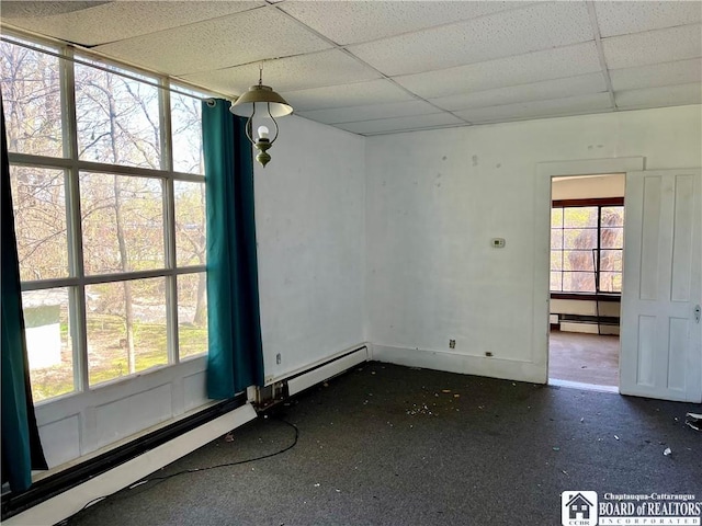 unfurnished dining area featuring a paneled ceiling and baseboard heating