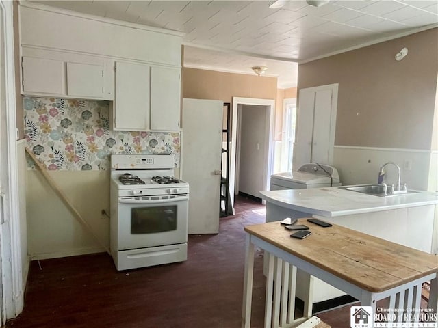 kitchen featuring a sink, white range with gas cooktop, washer / clothes dryer, white cabinetry, and light countertops