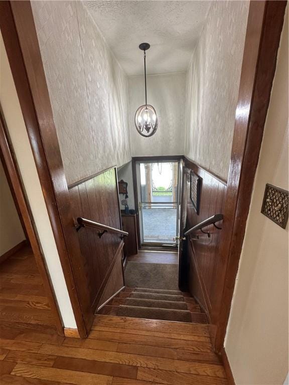 48 King St, Mentz, NY 13140 - staircase featuring a chandelier, hardwood / wood-style floors, a textured ceiling, and baseboards