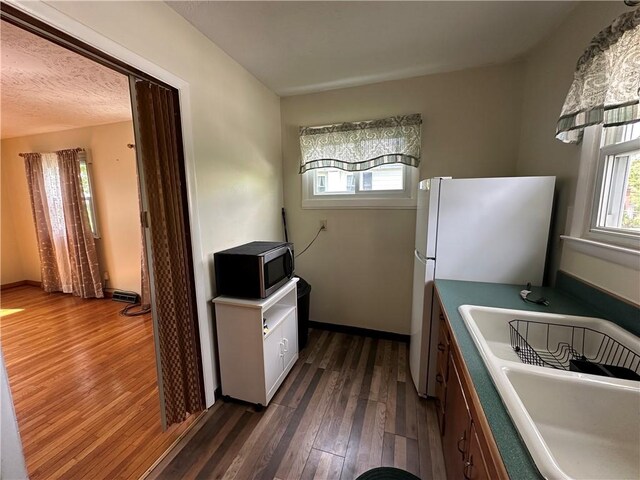 48 King St, Mentz, NY 13140 - kitchen with stainless steel microwave, a sink, dark wood-type flooring, freestanding refrigerator, and baseboards