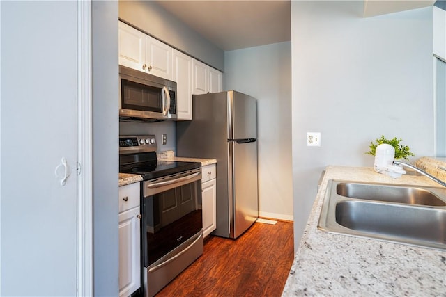 kitchen featuring white cabinets, a sink, appliances with stainless steel finishes, light countertops, and dark wood-type flooring