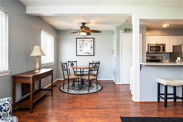 dining room with dark wood-type flooring, visible vents, a ceiling fan, and baseboards