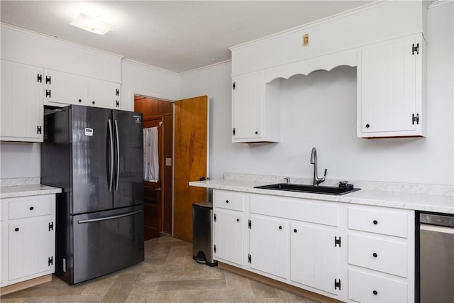 kitchen featuring a sink, white cabinetry, light countertops, ornamental molding, and freestanding refrigerator