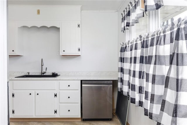kitchen featuring stainless steel dishwasher, a sink, white cabinets, and light countertops