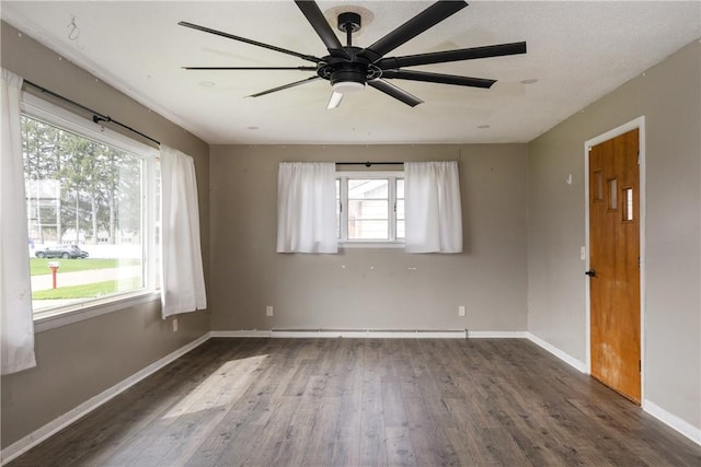 spare room with wood finished floors, a healthy amount of sunlight, ceiling fan, and baseboards