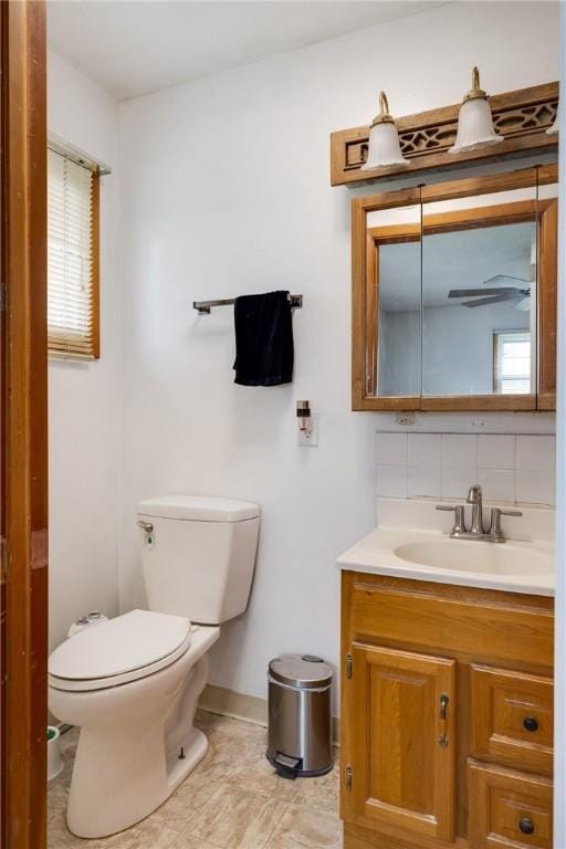 bathroom featuring baseboards, backsplash, toilet, and vanity