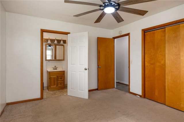 unfurnished bedroom featuring baseboards, light carpet, a closet, and a sink