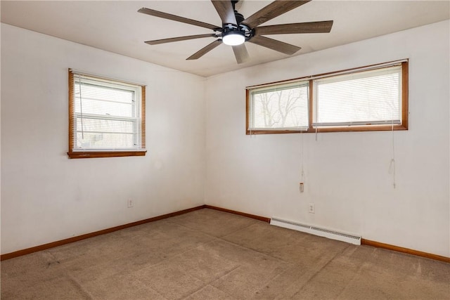 carpeted spare room featuring a ceiling fan, plenty of natural light, baseboard heating, and baseboards