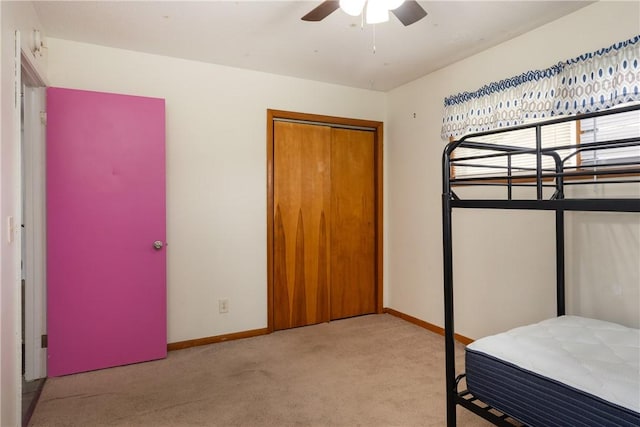 bedroom featuring baseboards, a ceiling fan, a closet, and carpet