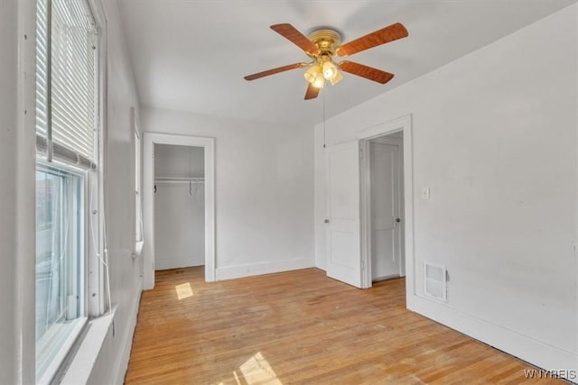 unfurnished bedroom with a closet, ceiling fan, light wood finished floors, baseboards, and visible vents