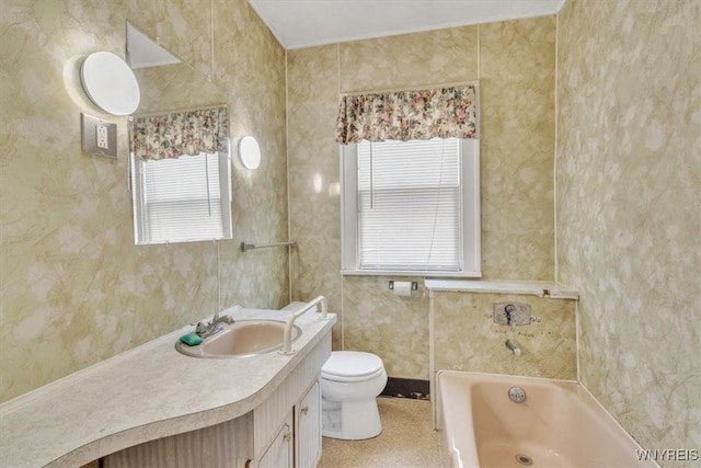 bathroom with toilet, a tub, vanity, and plenty of natural light