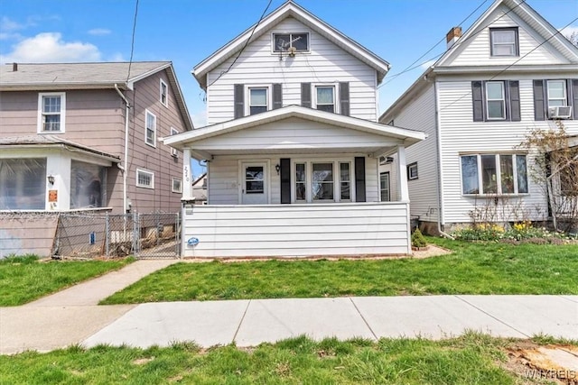 american foursquare style home with a porch, a gate, fence, cooling unit, and a front yard