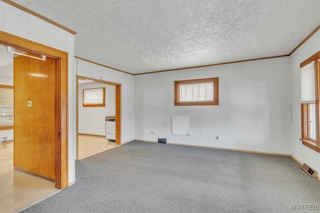 empty room with visible vents, ornamental molding, and carpet flooring