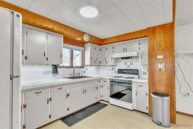 kitchen with a sink, backsplash, under cabinet range hood, and white appliances