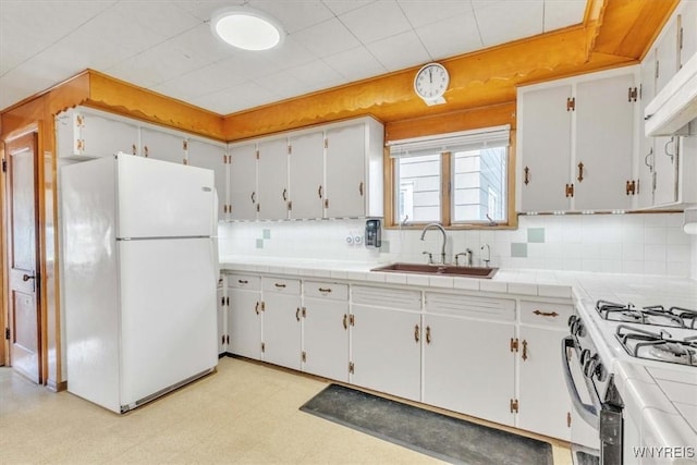 kitchen with light floors, white appliances, under cabinet range hood, backsplash, and a sink