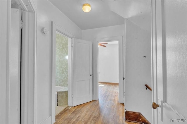 corridor featuring an upstairs landing and wood finished floors