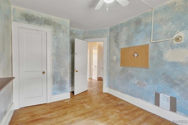 unfurnished room with wood finished floors, visible vents, ceiling fan, and baseboards
