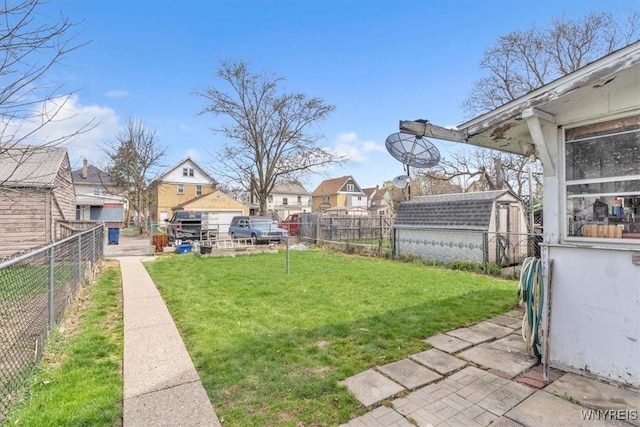view of yard featuring a storage shed, an outbuilding, a residential view, and a fenced backyard