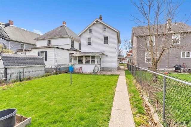 rear view of house with a chimney, a fenced backyard, and a yard