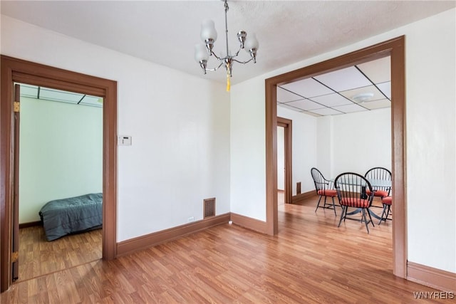dining space featuring visible vents, a paneled ceiling, baseboards, a chandelier, and light wood-style floors