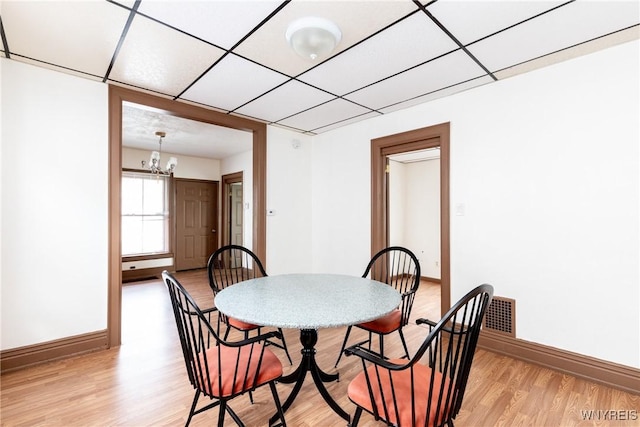 dining room featuring light wood-type flooring, baseboards, and an inviting chandelier