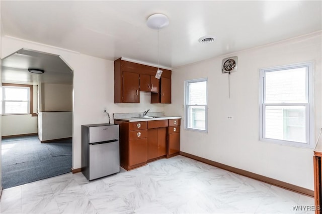 kitchen featuring freestanding refrigerator, a healthy amount of sunlight, a sink, and light countertops