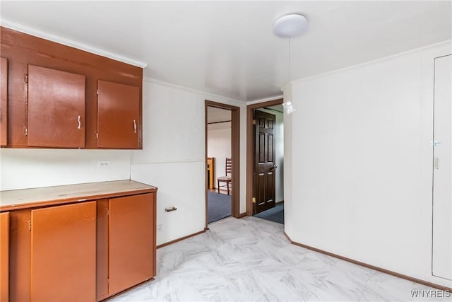 kitchen featuring light countertops, baseboards, crown molding, and brown cabinetry