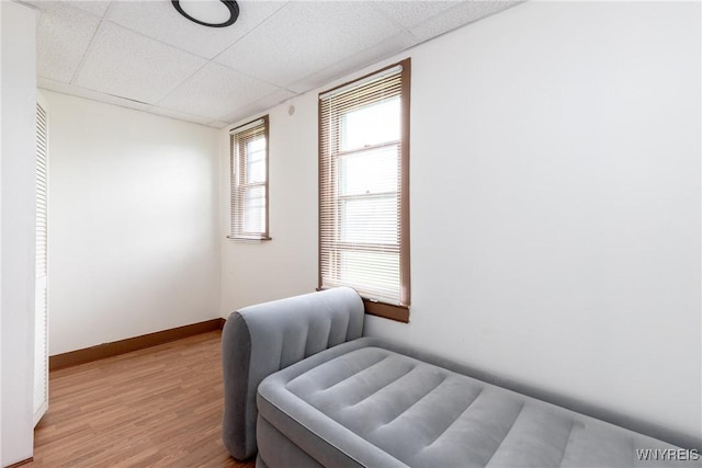 bedroom featuring baseboards, a paneled ceiling, and light wood-style floors