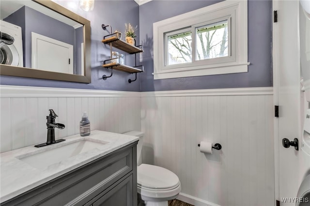 bathroom with vanity, toilet, and a wainscoted wall