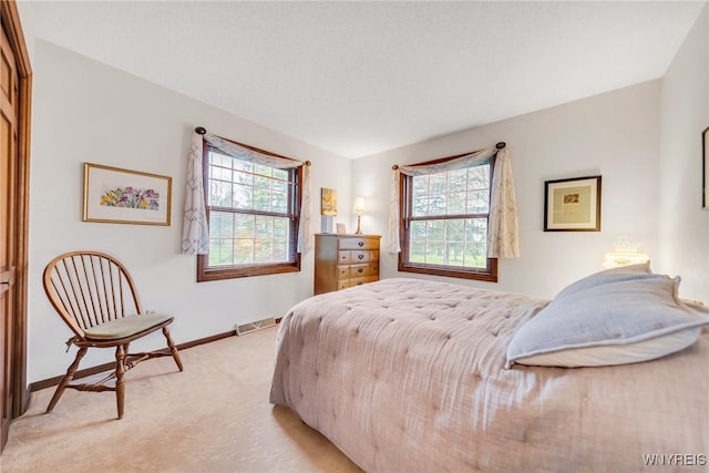 bedroom featuring baseboards, visible vents, light carpet, and multiple windows