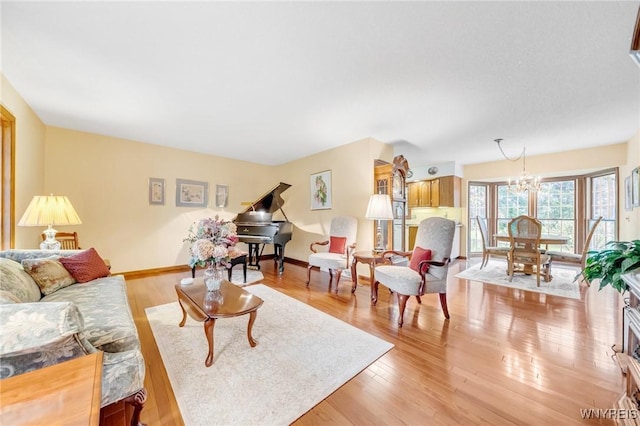living room with an inviting chandelier, baseboards, and light wood-style floors