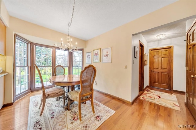 dining room featuring a wealth of natural light, light wood-style flooring, a chandelier, and baseboards