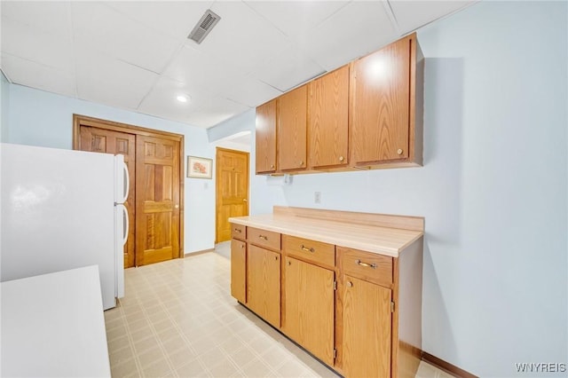 kitchen featuring light floors, freestanding refrigerator, light countertops, visible vents, and a paneled ceiling