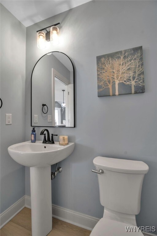 bathroom with baseboards, toilet, and a sink