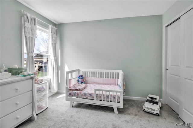 carpeted bedroom with baseboards, a nursery area, and a closet