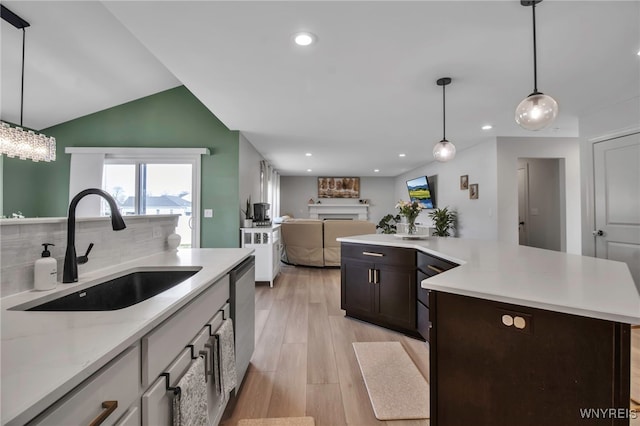 kitchen with recessed lighting, a sink, a fireplace, light wood-type flooring, and open floor plan