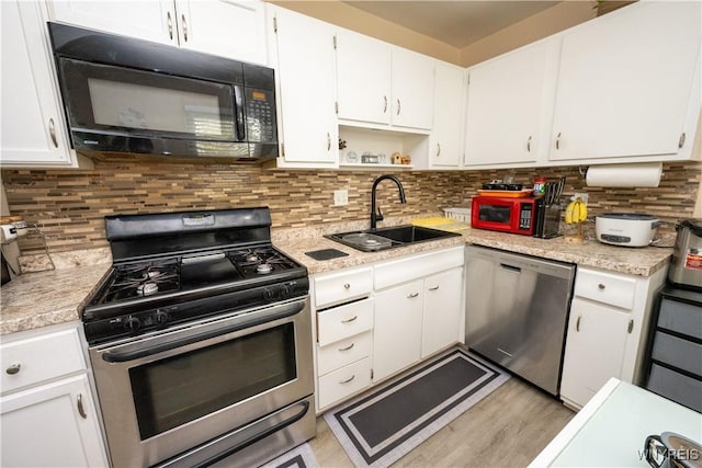 kitchen featuring white cabinetry, stainless steel appliances, light countertops, and a sink