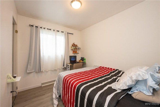 bedroom featuring baseboard heating, wood finished floors, and baseboards