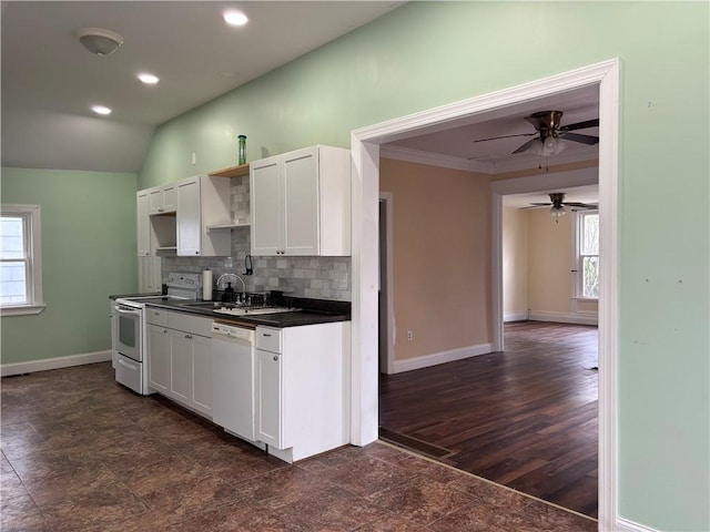 kitchen featuring white appliances, white cabinets, dark countertops, ceiling fan, and a sink