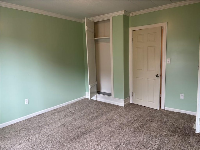 unfurnished bedroom with baseboards, dark colored carpet, ornamental molding, and a closet